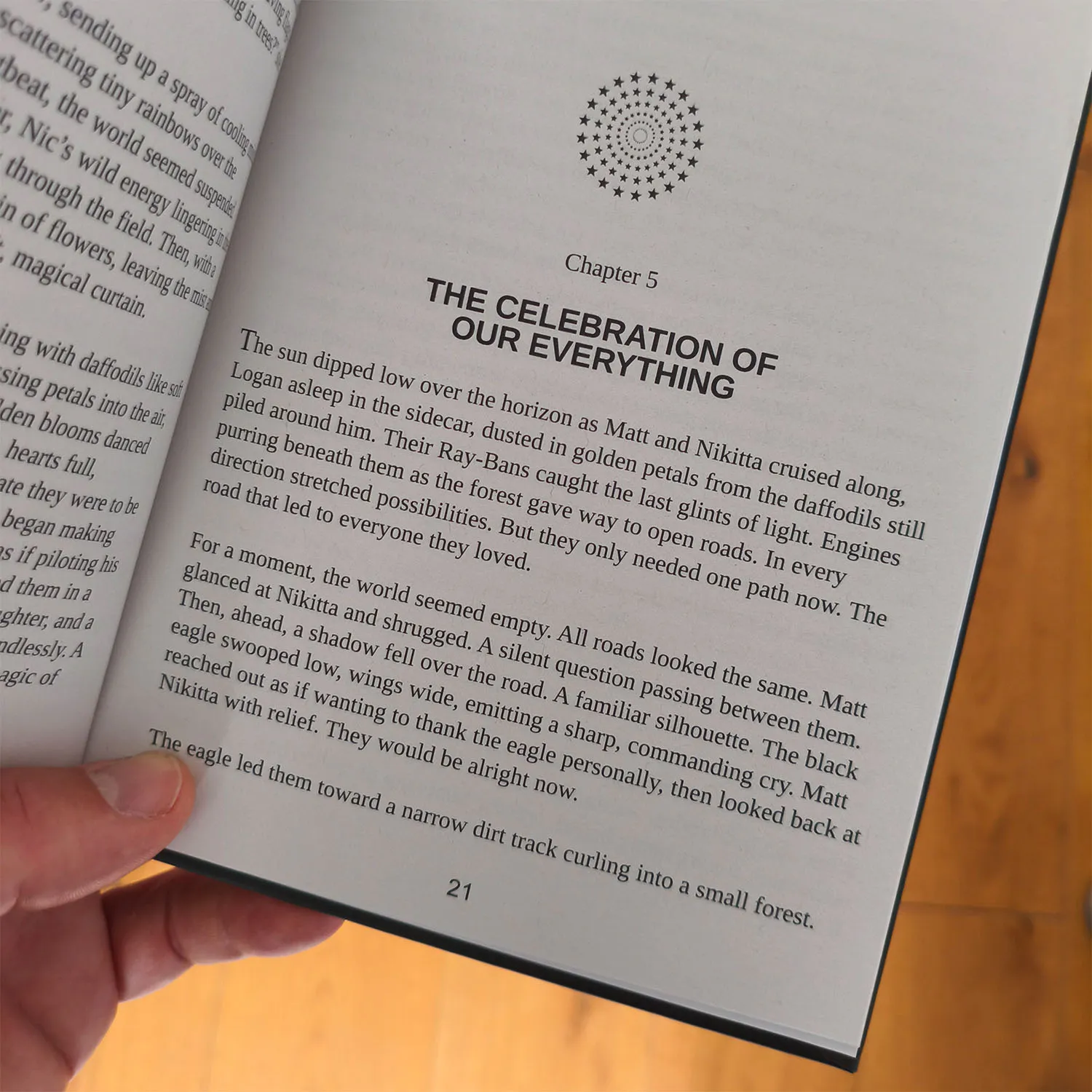 A hand holds open a book to page 21, revealing Chapter 5, "THE CELEBRATION OF OUR EVERYTHING," with a decorative circle above. The text describes a sunset drive and the uncertainty that shapes Your Legendary Tale.