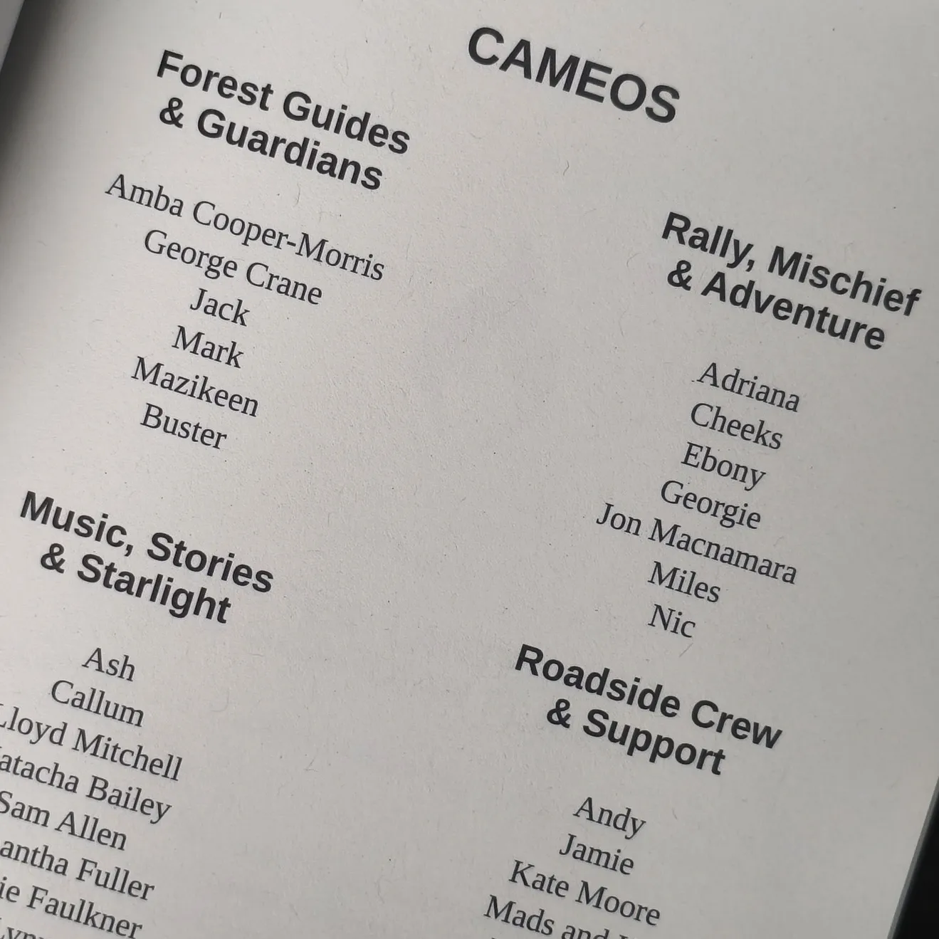 A close-up of a book page titled "CAMEOS" lists names under Forest Guides & Guardians, Rally, Mischief & Adventure, Music, Stories & Starlight, and Roadside Crew & Support—each a part of Your Legendary Tale.
